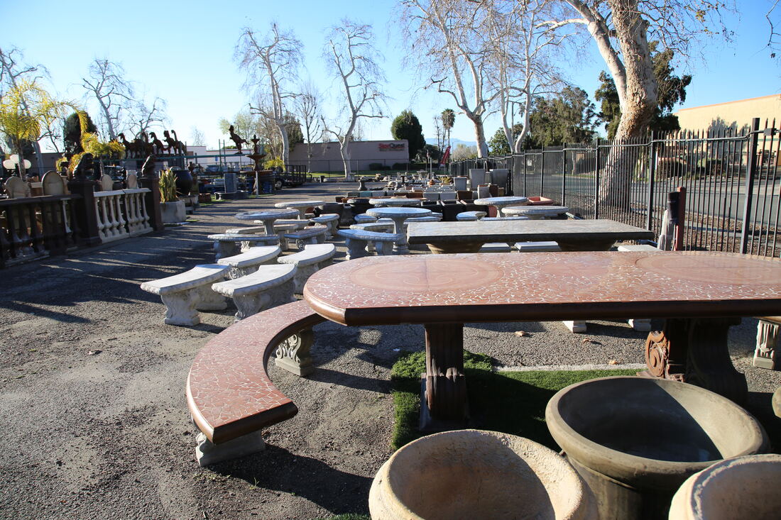 Polished stone tables and curved benches arranged on the gravel.