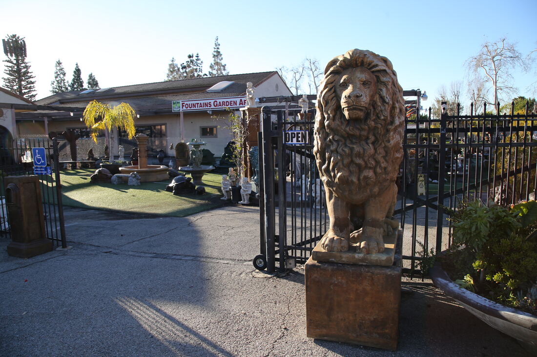 A carved stone lion on a plinth beside the wrought-iron entrance gate.