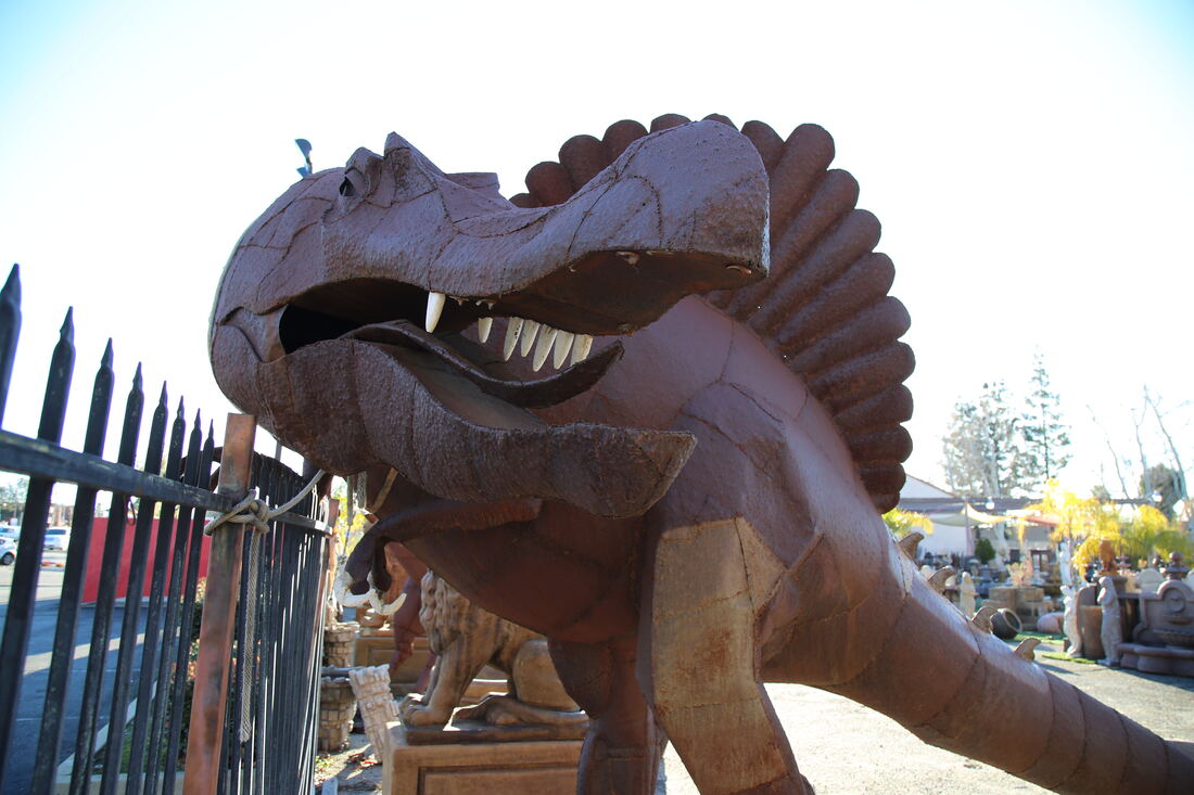 A large rust-finished metal dinosaur sculpture behind the yard fence.