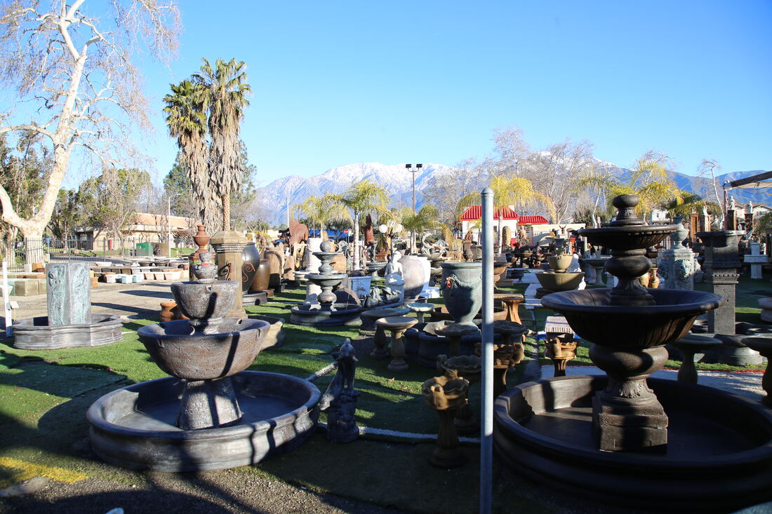 Rows of dark stone fountains and basins filling the yard, San Gabriel Mountains in the distance.