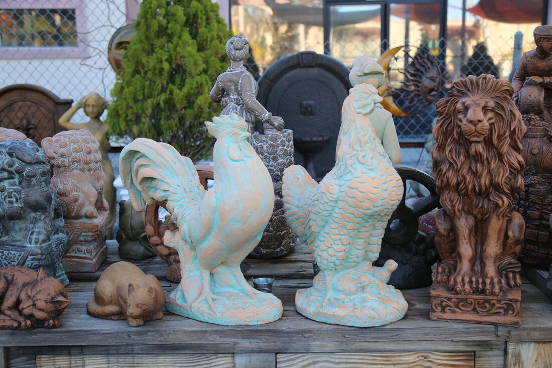 Turquoise-glazed roosters and a terracotta lion on a display table.